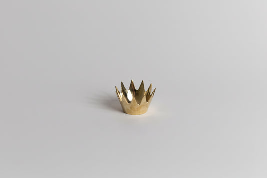 Gold crown-shaped object on a light gray background