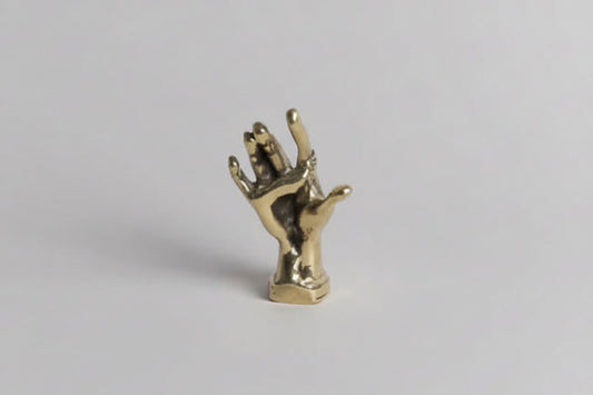 brass-colored hand sculpture on a light gray background