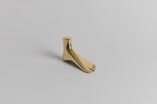 Gold foot charm on a light gray background