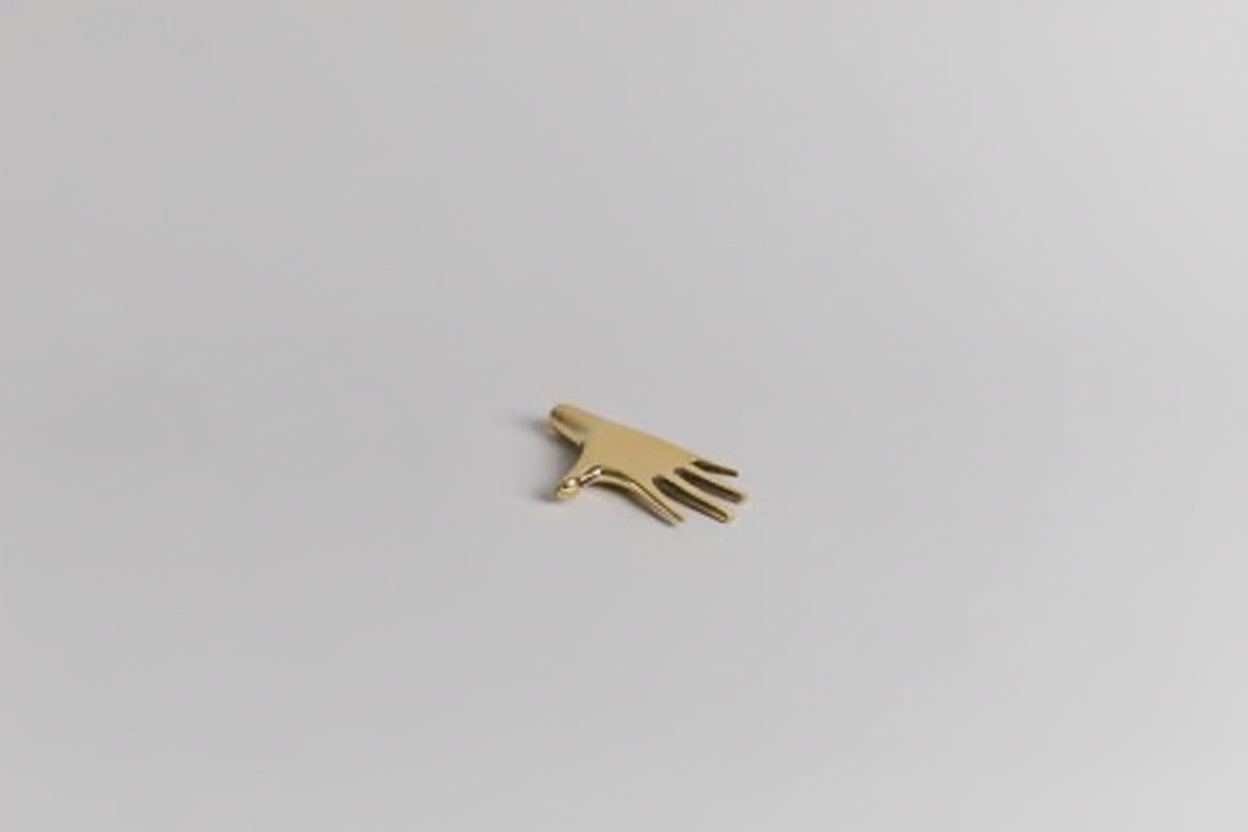 Small gold hand-shaped object on a light gray background