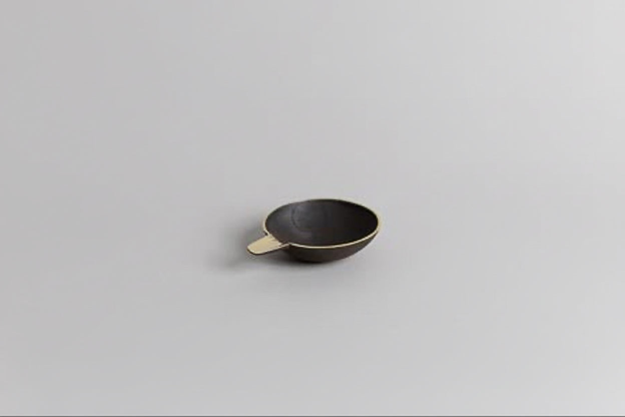 Small black brass dish on a light gray background