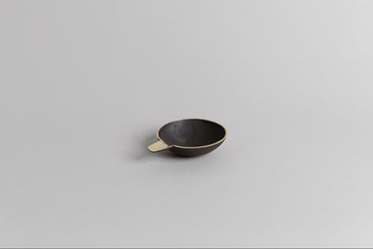 Small black brass dish on a light gray background