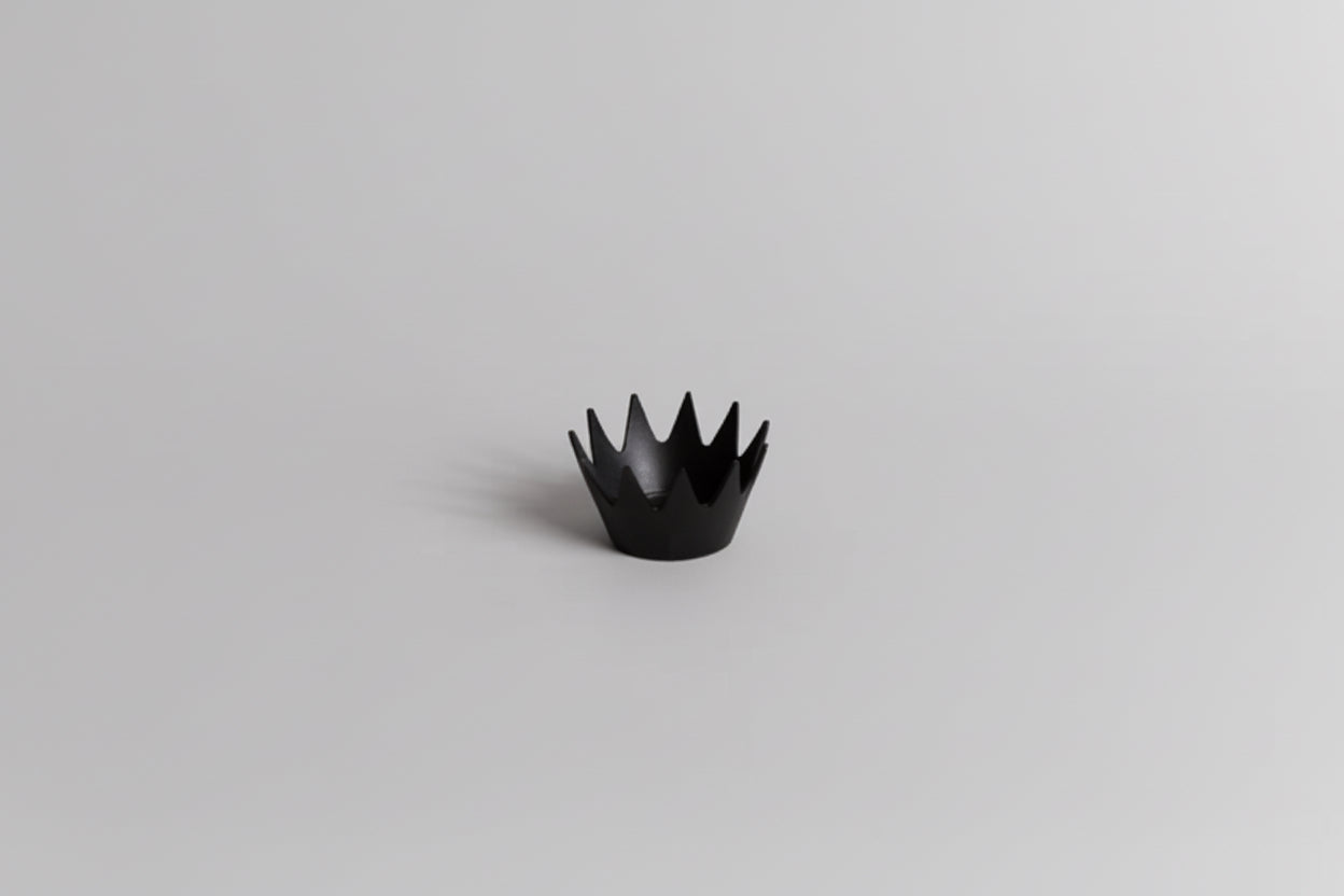 Black crown-shaped object on a light gray background